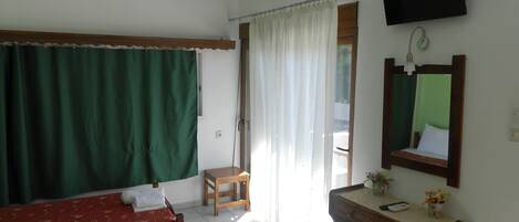 Una habitación con dos camas, un escritorio, una silla, un televisor y una ventana con cortinas.