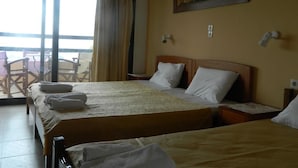 A hotel room with two beds, a balcony with chairs, and a painting on the wall. - Asteri Studio's (Skiathos)
