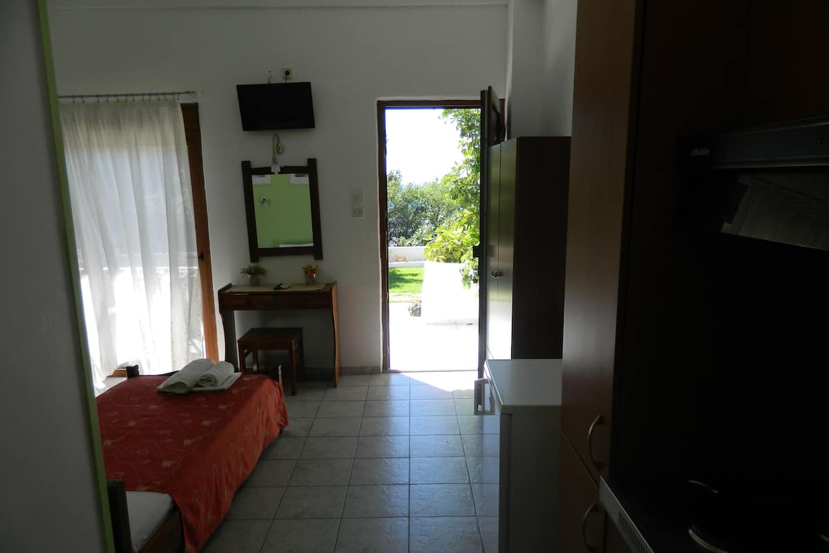 A hotel room with a bed, a desk, a chair, a television, and a view of the outdoors.
