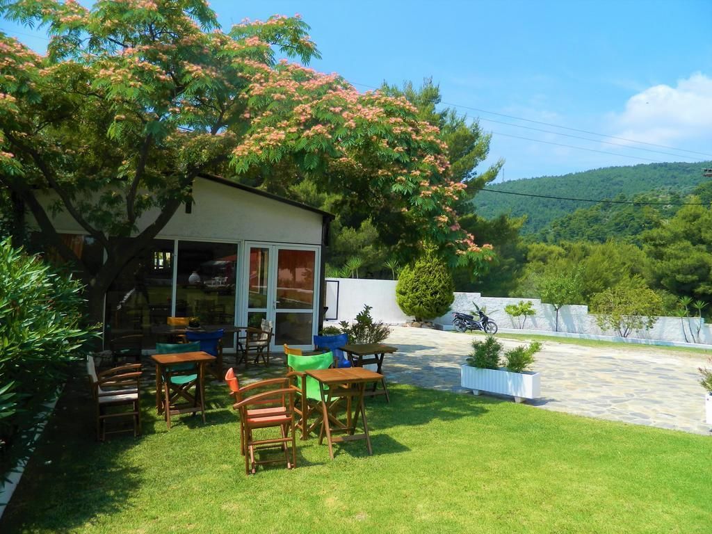 A small house with a patio area, outdoor seating, and a view of a hilly landscape.