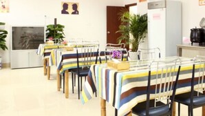 A dining area with striped tablecloths, chairs, and a refrigerator. - GreenTree Inn Nanjing Lishui District Lishui Airport Road Express Hotel (Nanjing)