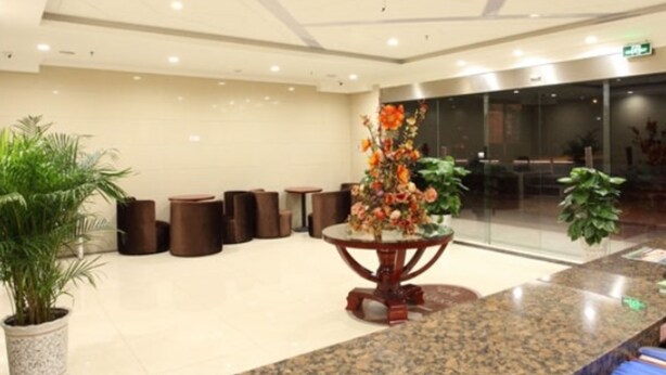 A lobby with a granite reception desk, several potted plants, and a modern ceiling design. - GreenTree Inn Nanjing Lishui District Lishui Airport Road Express Hotel (Nanjing)