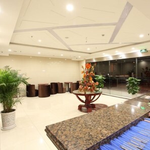 A lobby with a granite reception desk, several potted plants, and a modern ceiling design. - GreenTree Inn Nanjing Lishui District Lishui Airport Road Express Hotel (Nanjing)