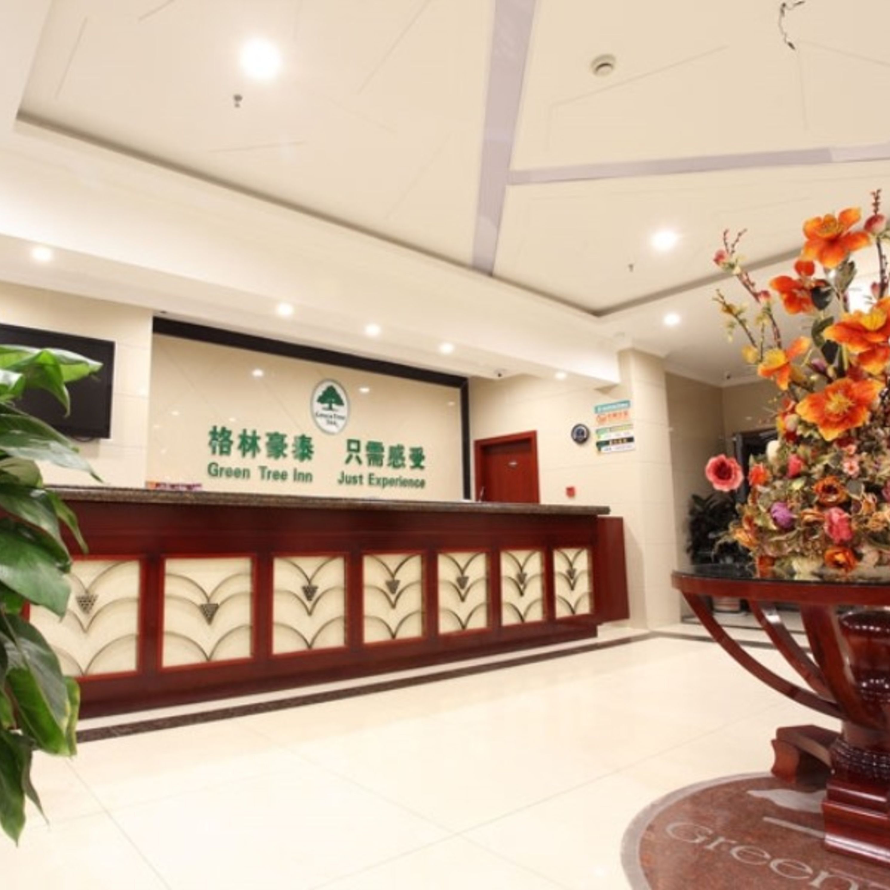 A reception desk with a sign for Green Tree Inn and a floral arrangement.