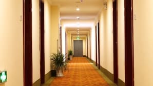 A hotel hallway with a carpeted floor, wooden doors, and a green plant. - GreenTree Inn Nanjing Lishui District Lishui Airport Road Express Hotel (Nanjing)