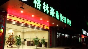 A hotel entrance with a green sign, glass doors, and potted plants outside. - GreenTree Inn Nanjing Lishui District Lishui Airport Road Express Hotel (Nanjing)