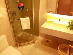 Un baño con cabina de ducha de vidrio, un lavabo blanco con un espejo encima y una toalla colgada en la pared.