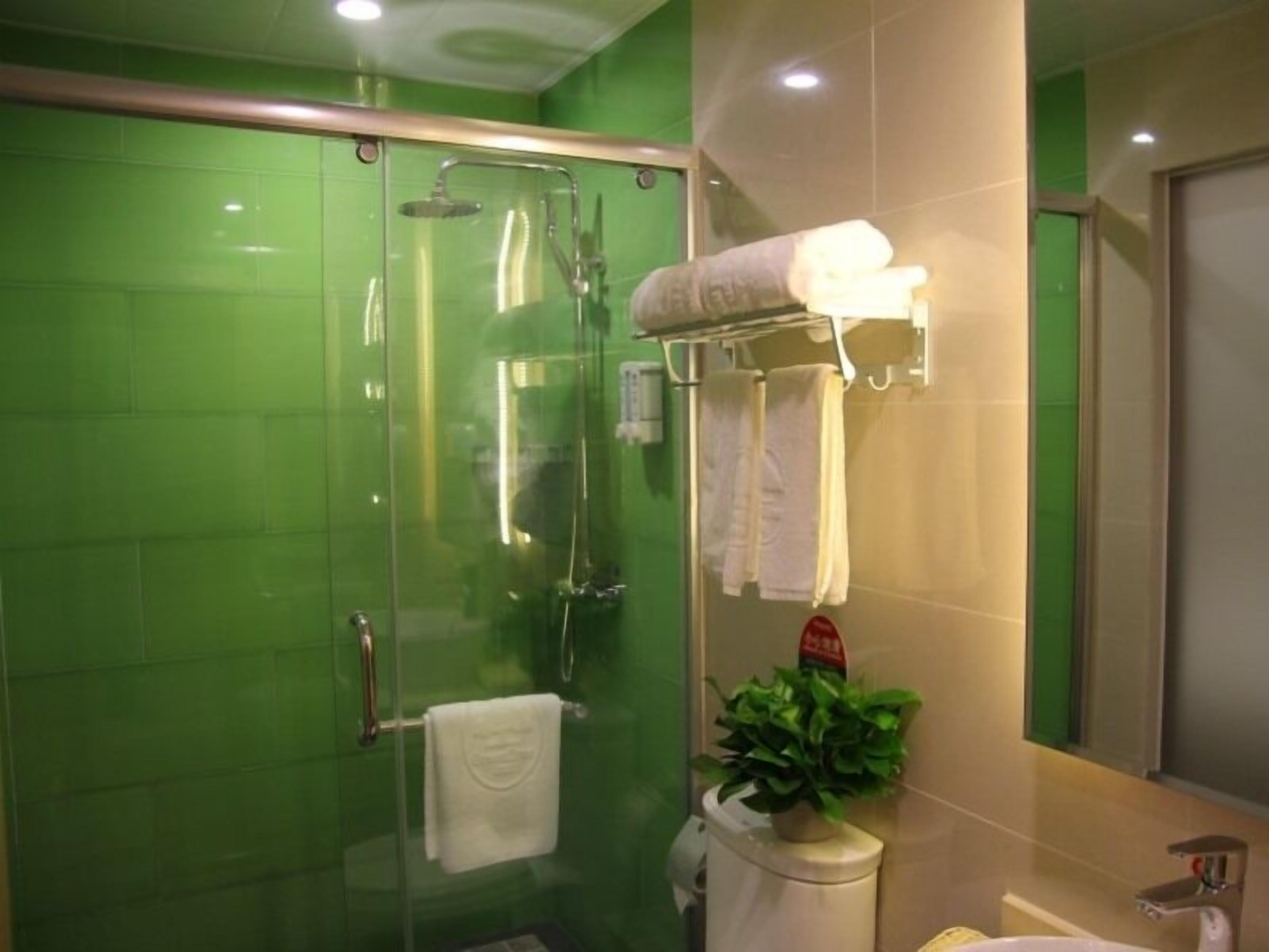 A glass-enclosed shower with a handheld showerhead, a glass door, and a towel rack with two towels.