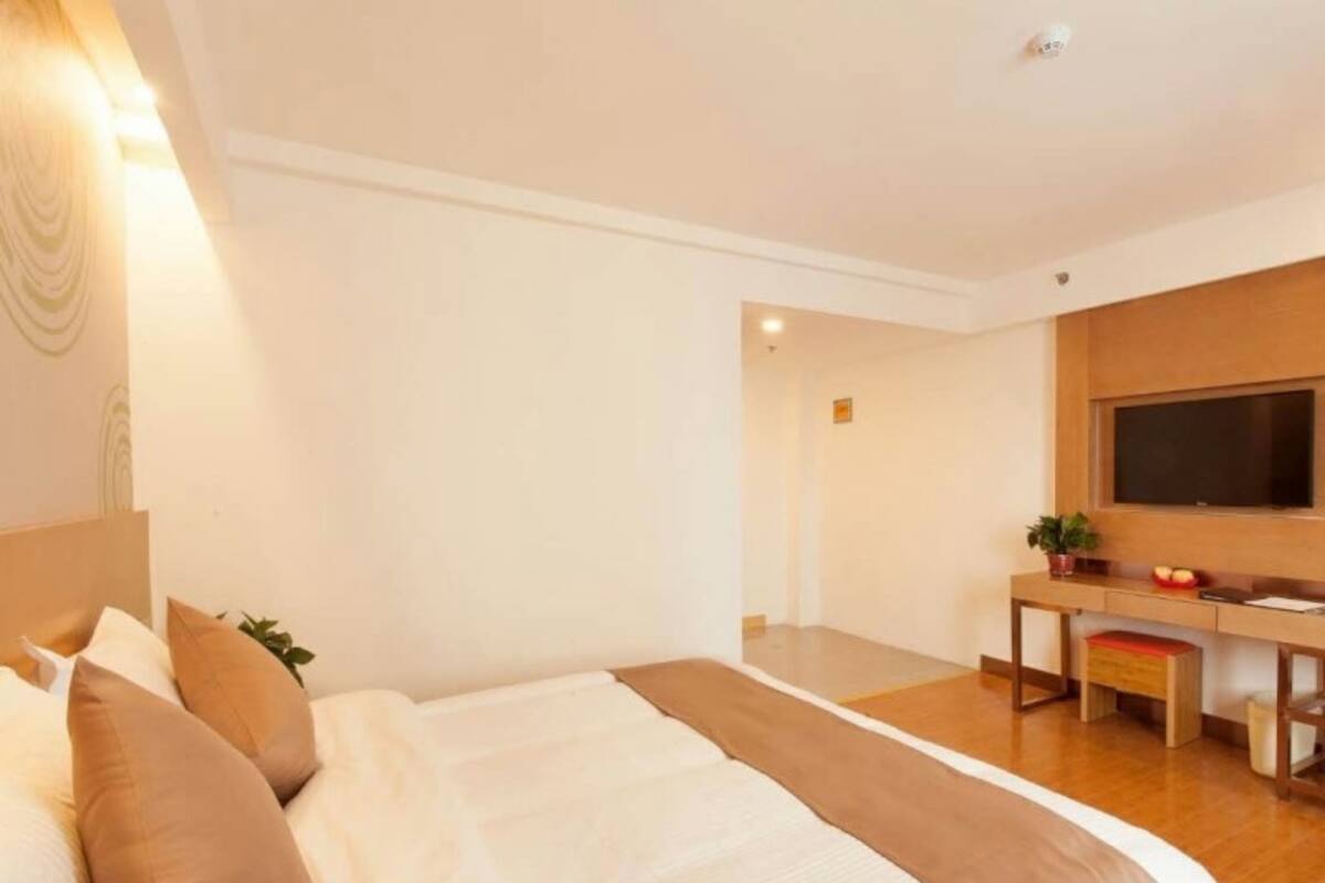 Una habitación de hotel con una cama grande, un escritorio y un televisor.