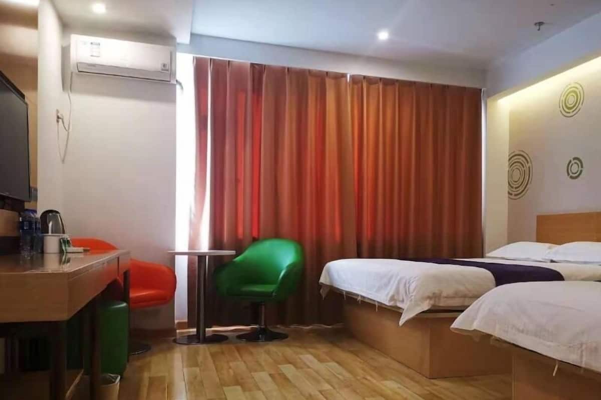 Habitación de hotel con suelo de madera, un escritorio con silla, cama y cortina.