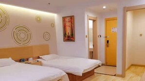 Habitación de hotel con dos camas, suelo de madera, un cuadro en la pared y una puerta a la derecha.