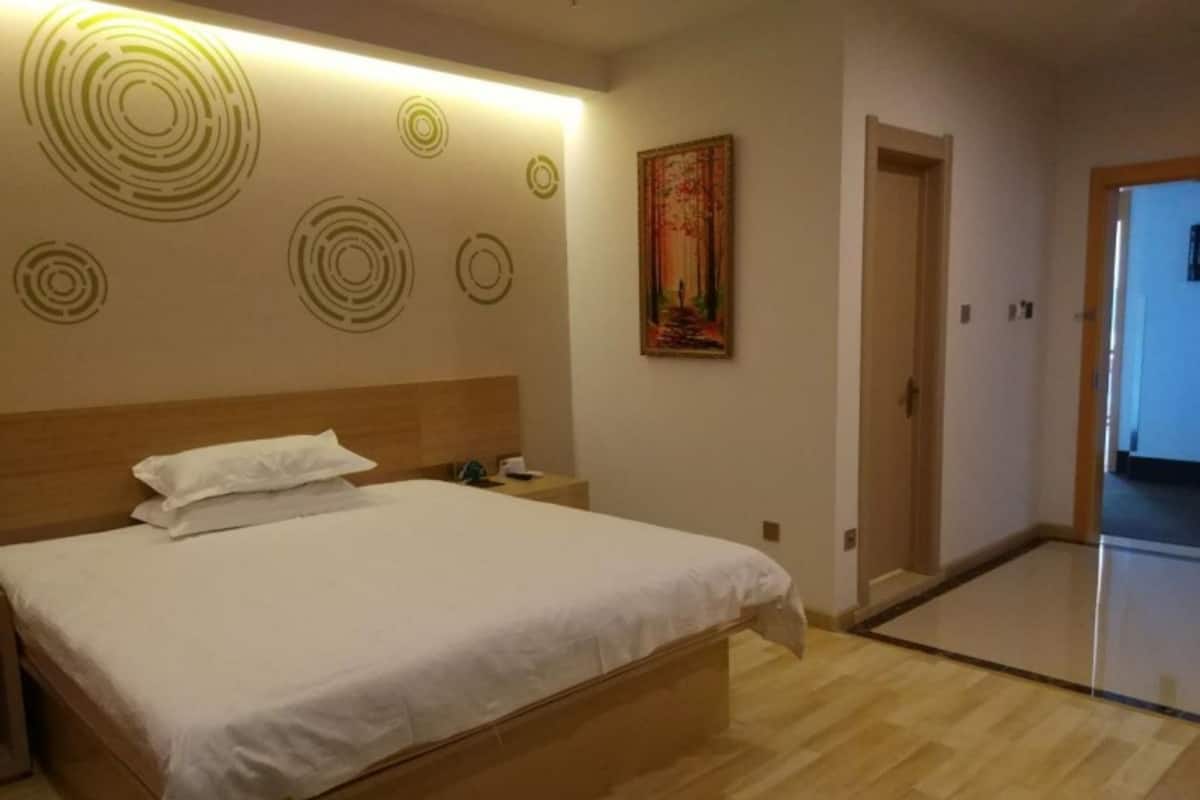 Habitación de hotel con una cama grande, una mesita de noche, una pared con diseños circulares y un cuadro.