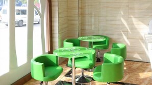 A corner of a room with green chairs and a table, a window with a view of the street, and a sign on the wall. - Vatica Shanghai Jinshan District Jinshan Guojishangmaocheng Weihong Road Hotel (Shanghai)