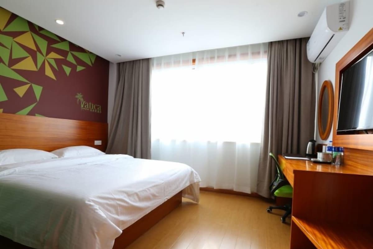 Una camera d'albergo con un letto, una scrivania e una finestra con tende.
