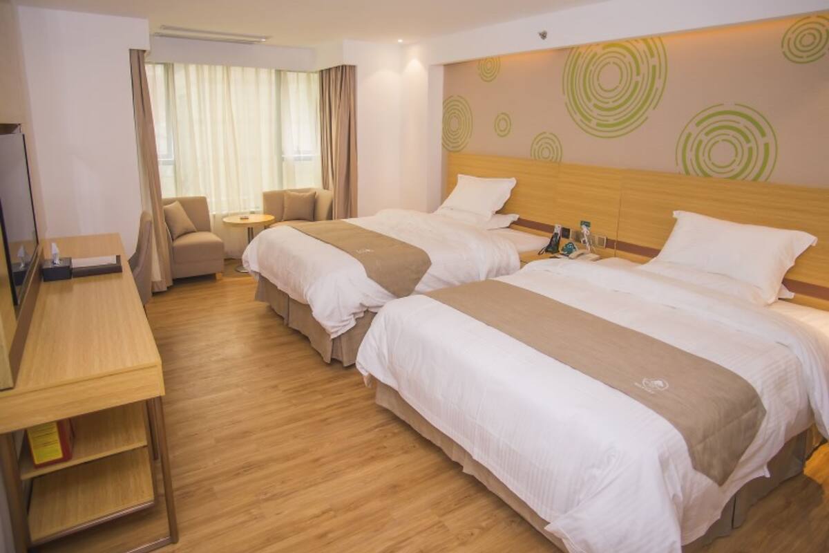 A hotel room with two beds, a desk, a chair, and a small table.