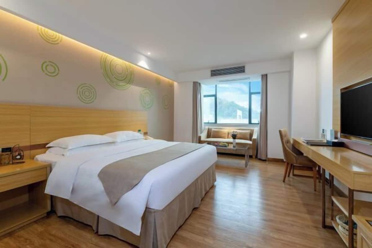 A hotel room with a bed, desk, chair, and television.
