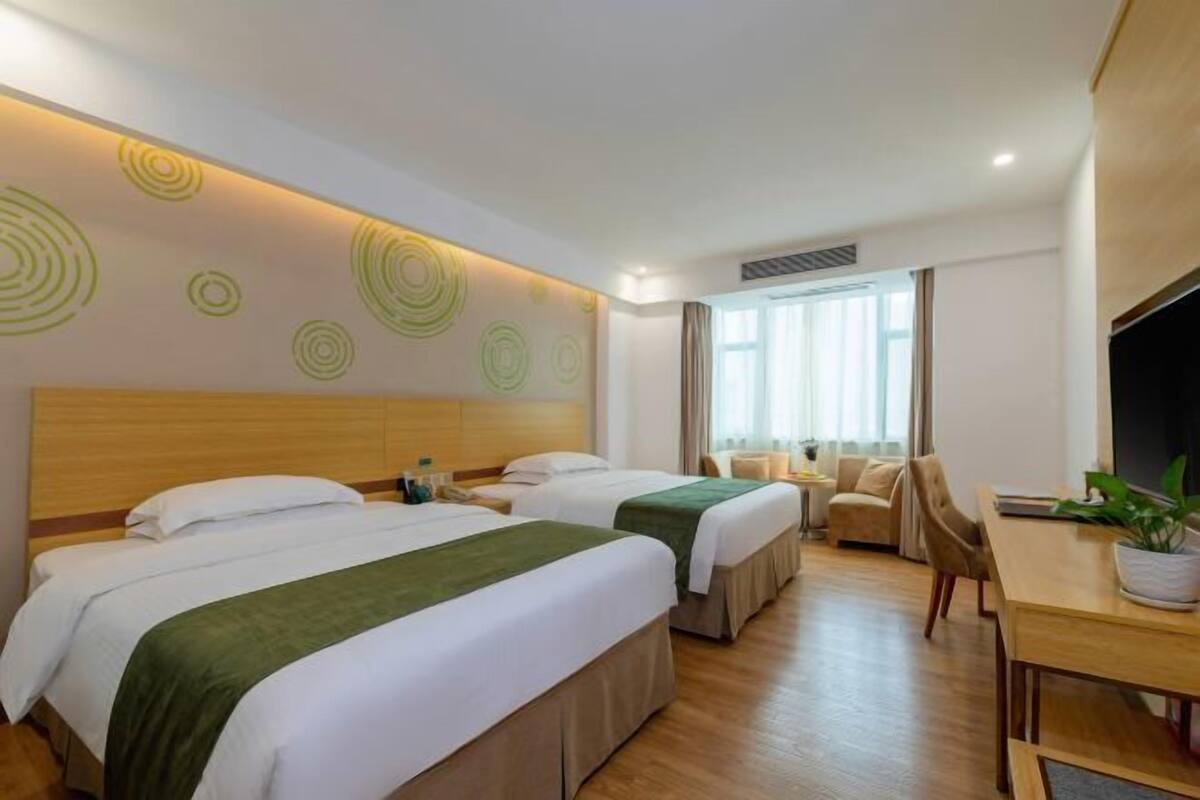 A hotel room with two beds, a dining table, a TV, and a window with curtains.