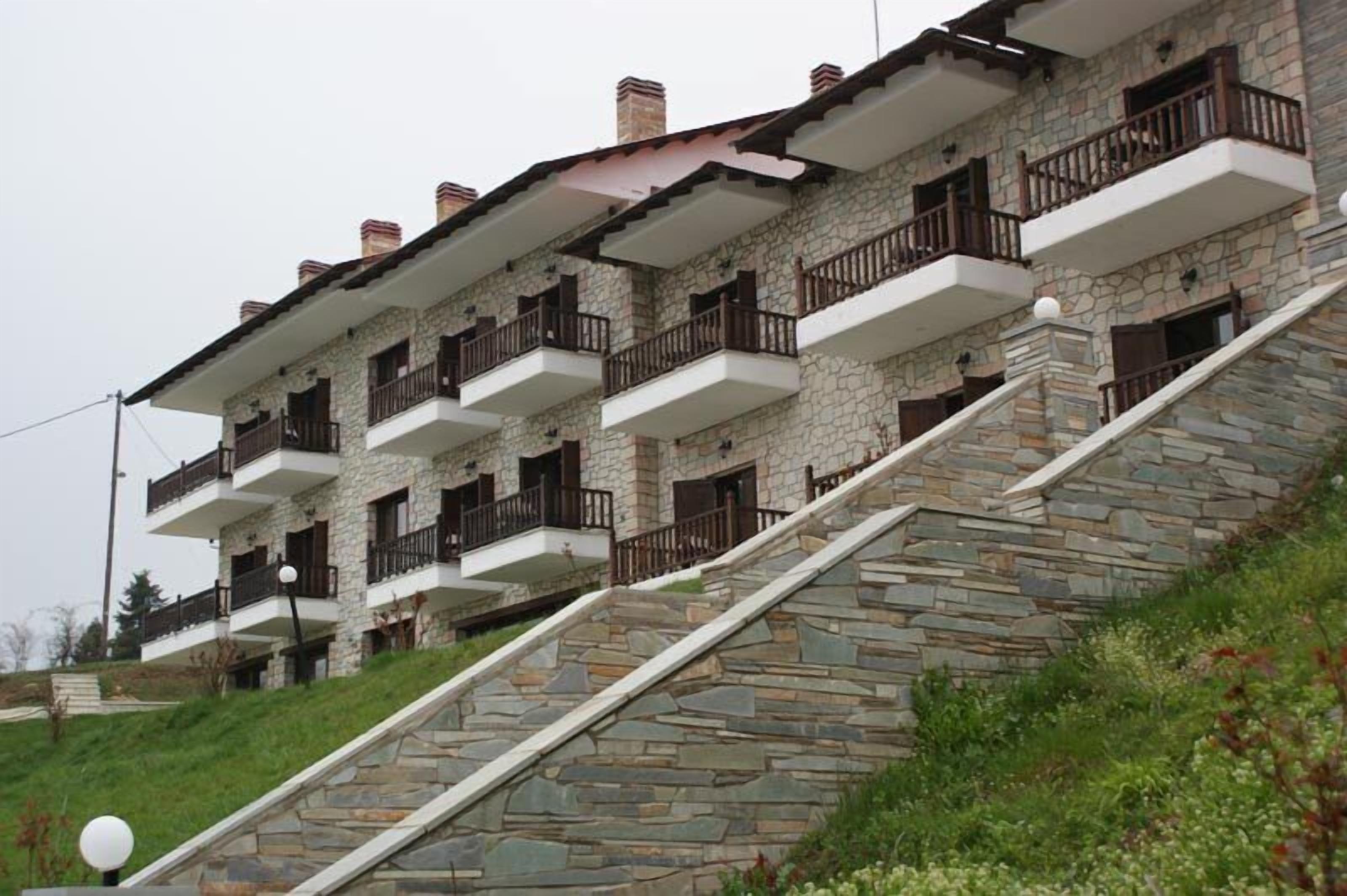 Un immeuble en pierre à plusieurs étages, doté de balcons et d’un escalier menant à l’entrée.