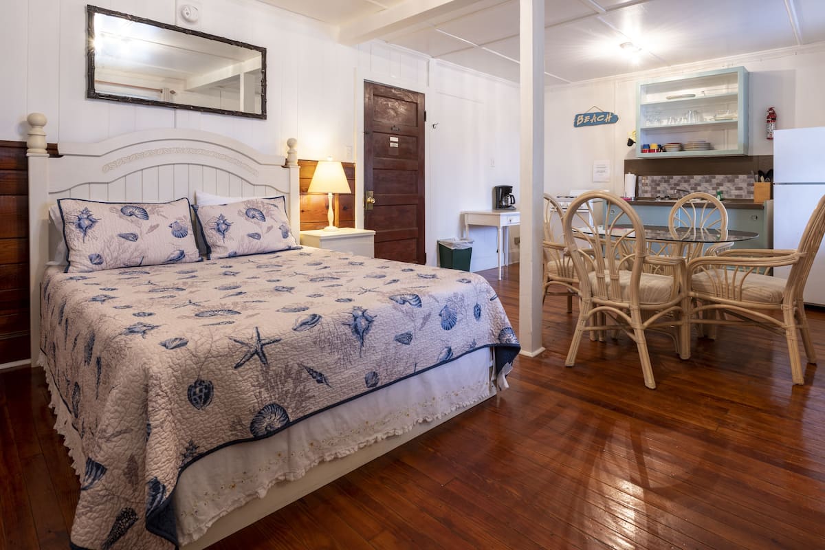 Une chambre à coucher comprenant un lit, une table de chevet, une lampe et un petit bureau avec une chaise.