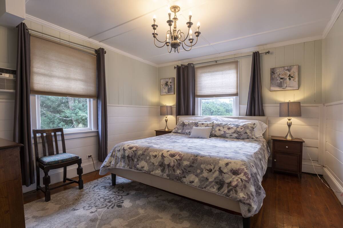 Une chambre à coucher avec un grand lit, deux tables de chevet, une chaise et un lustre.