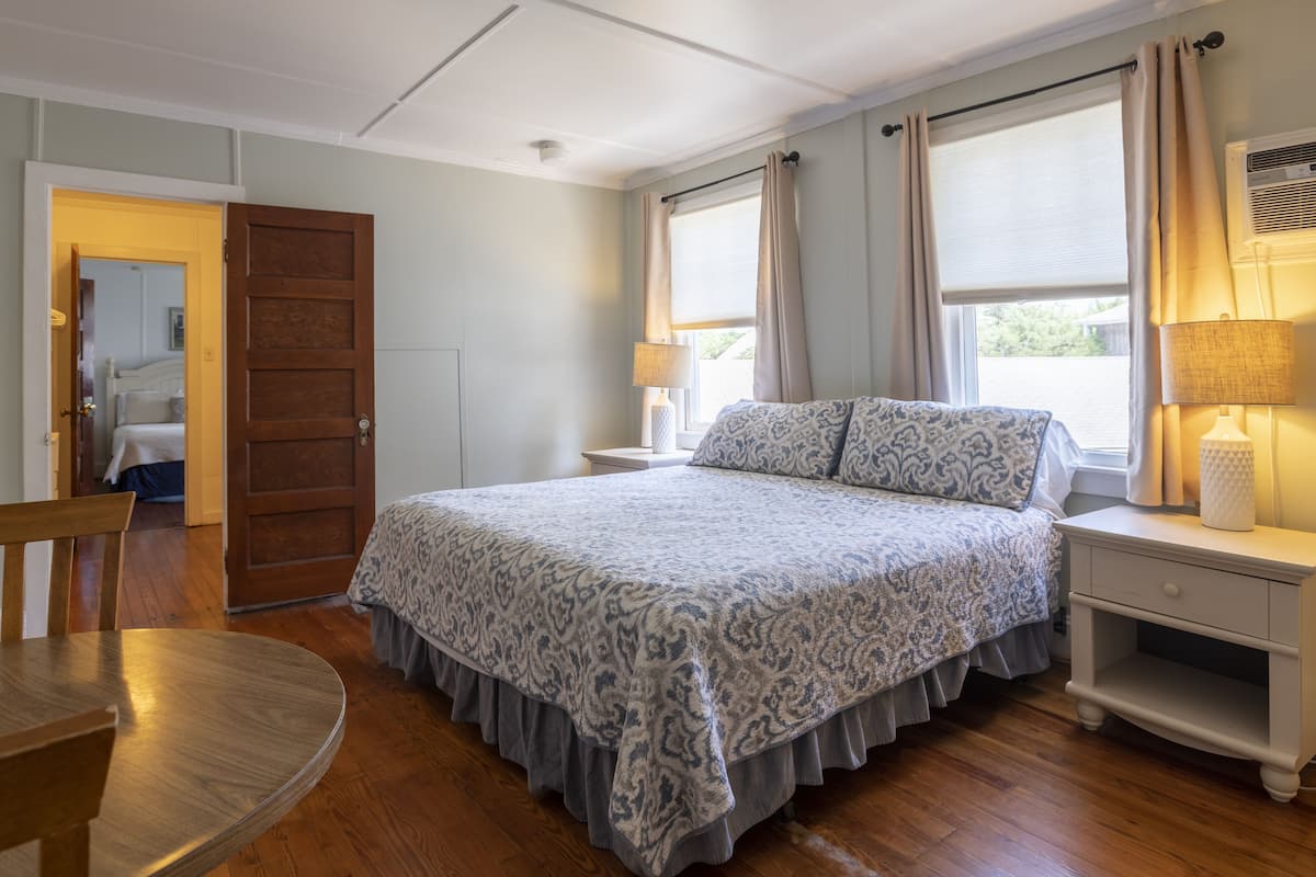 Une chambre à coucher avec un grand lit, deux tables de chevet, une chaise et une fenêtre avec des rideaux.