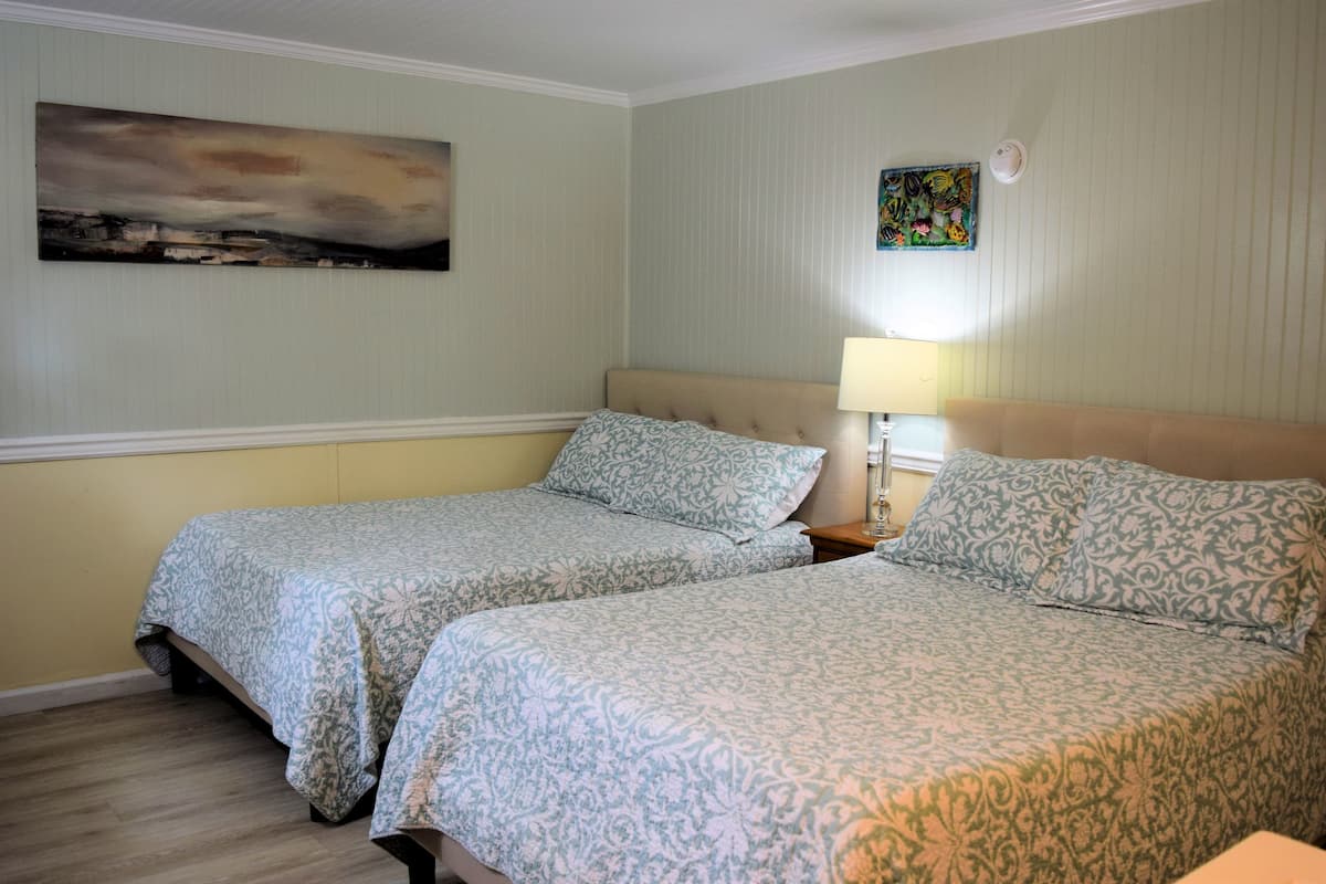 Une chambre d’hôtel avec deux lits, une table de chevet avec une lampe et un tableau au mur.