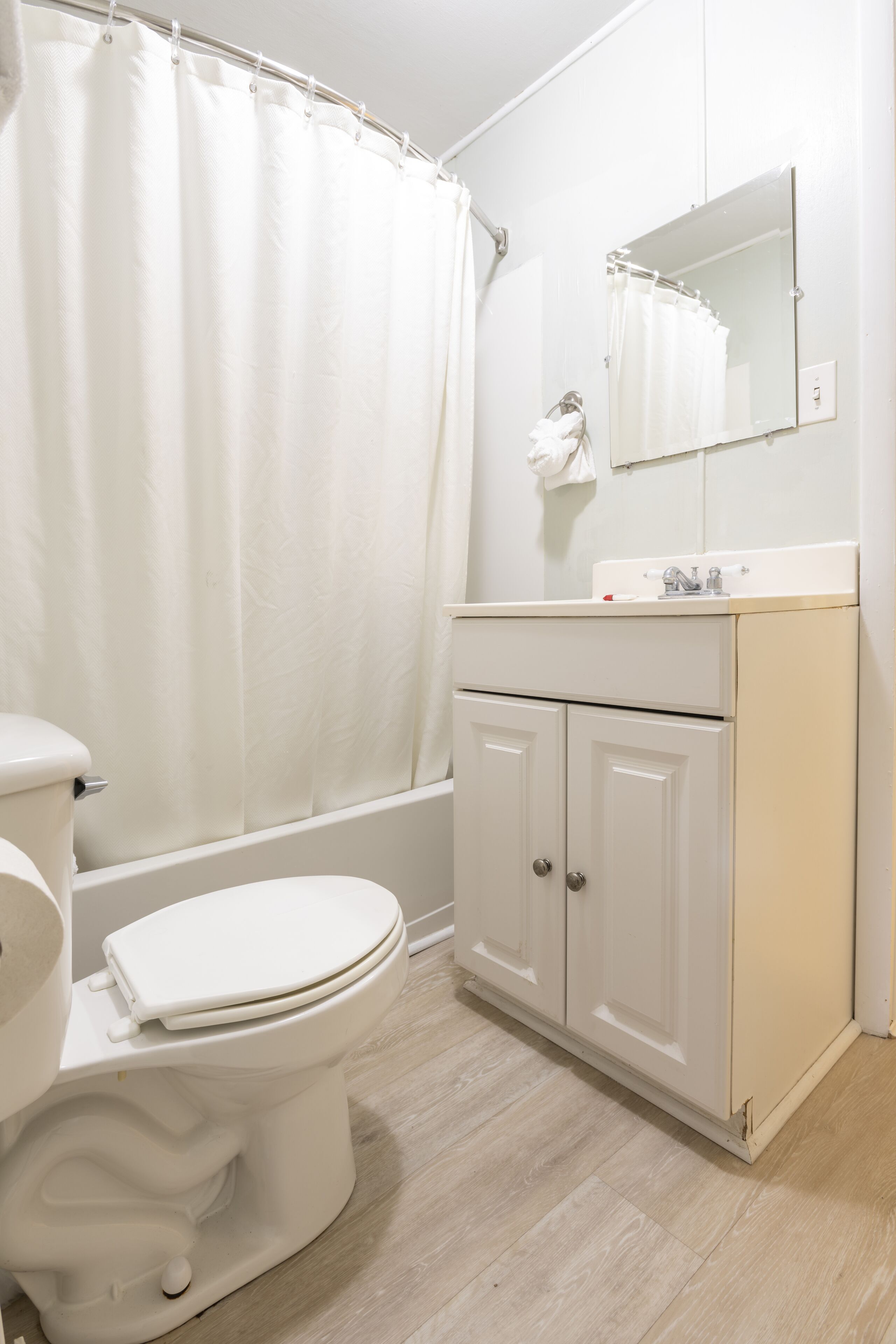 A bathroom with a toilet, a bathtub, a sink, and a mirror.