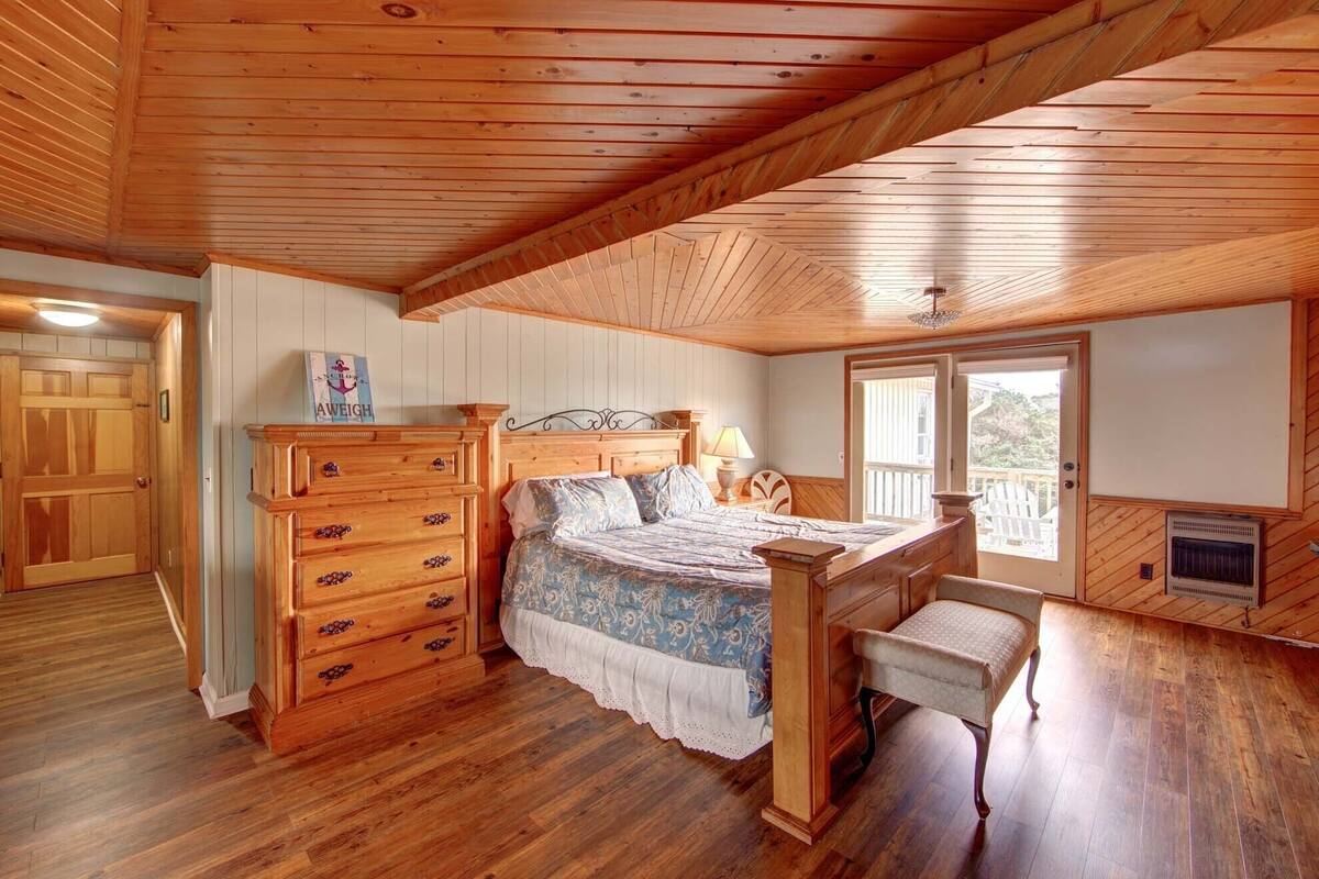 Une chambre à coucher aux murs lambrissés, avec un lit, une commode et un banc.