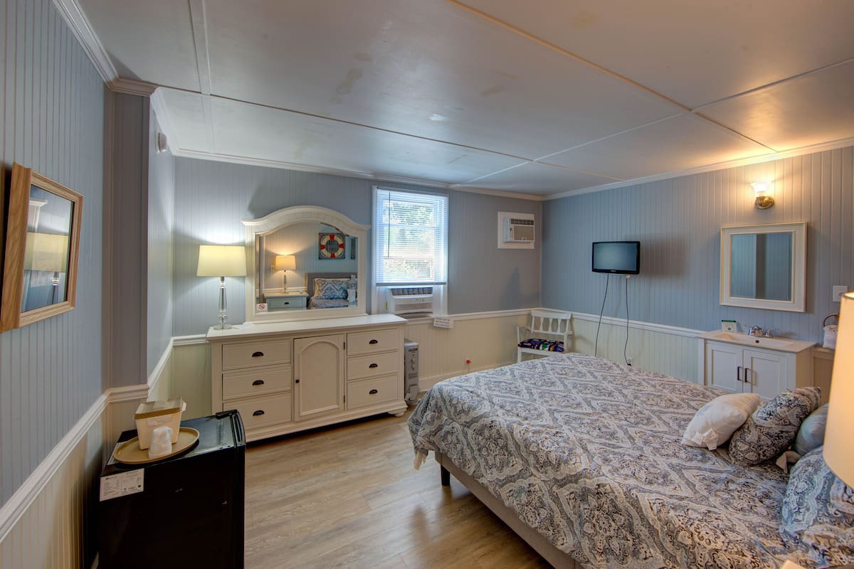 Une chambre à coucher comprenant un lit, une commode, une coiffeuse et un téléviseur.