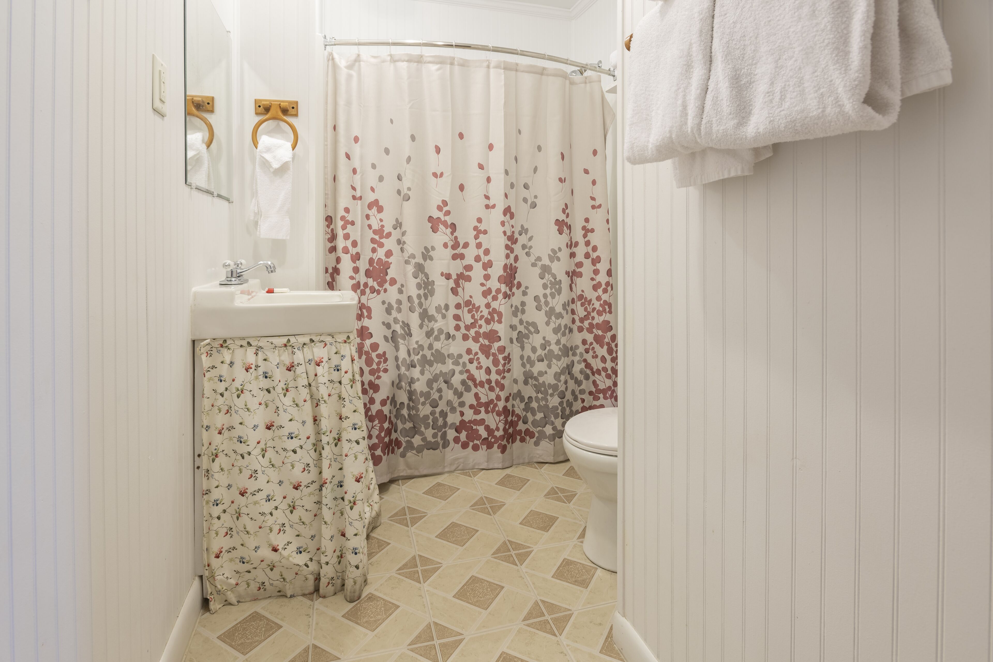 A bathroom with a shower curtain, a toilet, and a sink.