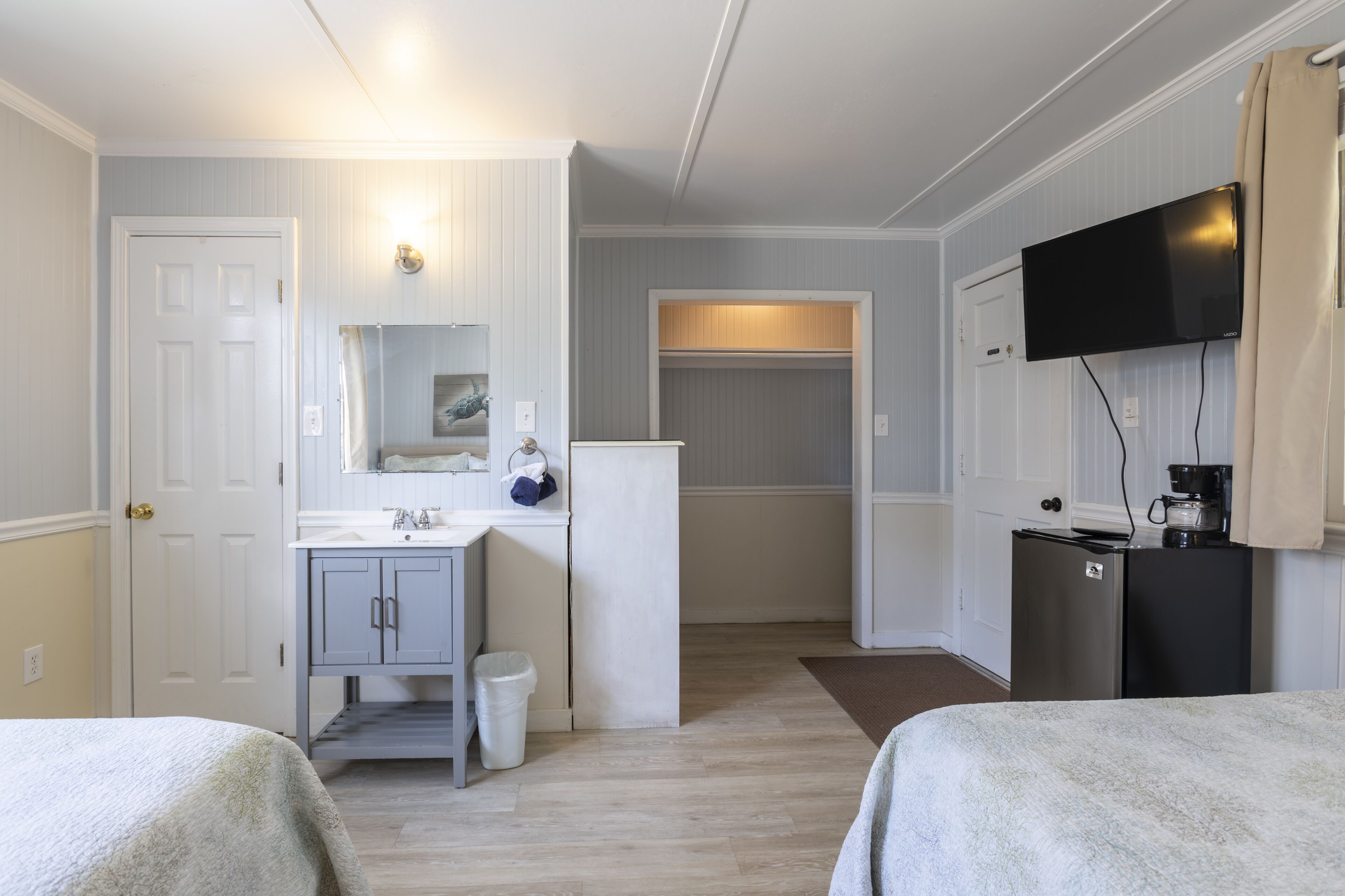 Una habitación de hotel con una cama, un pequeño rincón de cocina, un televisor y un baño.