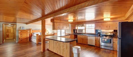 A spacious kitchen with wooden cabinets, a central island, and a refrigerator.