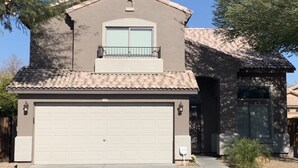 A two-story house with a garage, a balcony, and a stone facade.