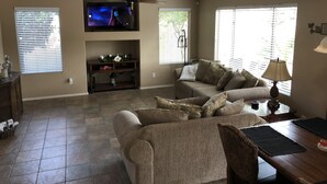 A living room with a TV, sofa, and a ceiling fan.
