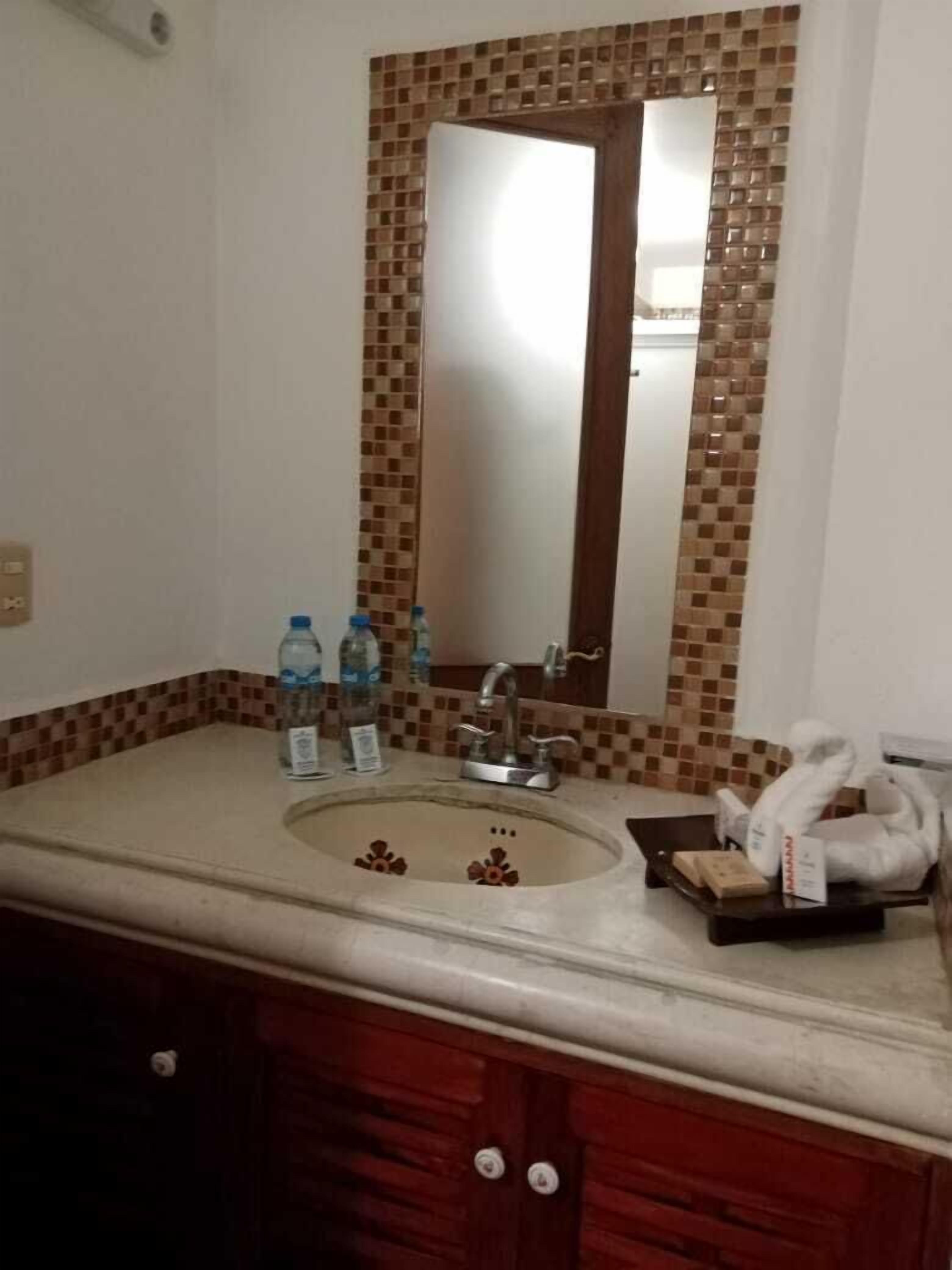 A bathroom with a sink, mirror, and toiletries.