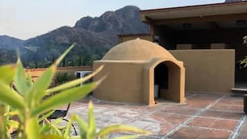 A patio area with a stone floor, a small covered structure, and a mountainous backdrop.