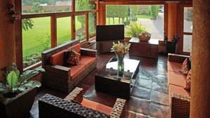 A spacious living area with wicker furniture, a glass coffee table, and a flat-screen TV. - Hotel Real del Valle Tepoztlan (Tepoztlán)