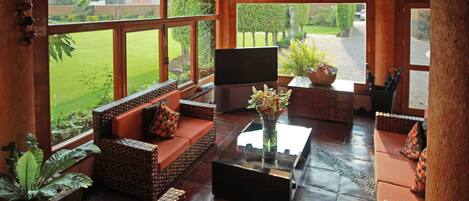 A spacious living area with wicker furniture, a glass coffee table, and a flat-screen TV.