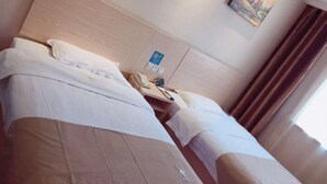 A hotel room with two beds, a wooden headboard, a painting on the wall, a telephone, and a window with curtains. - GreenTree Inn Shanghai Songjiang District Sijing Town Sijing Metro Station Express Hotel (Shanghai)