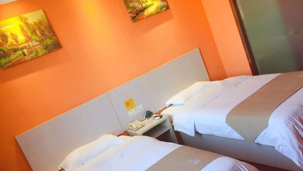 A hotel room with two beds, a nightstand, and a painting on the wall. - GreenTree Inn Shanghai Songjiang District Sijing Town Sijing Metro Station Express Hotel (Shanghai)