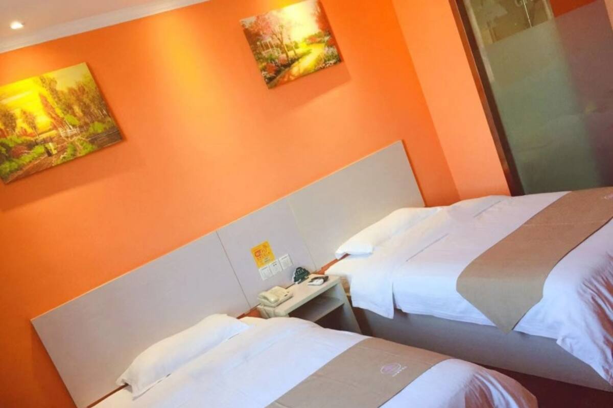 Una habitación de hotel con dos camas, una mesita de noche y un cuadro en la pared.