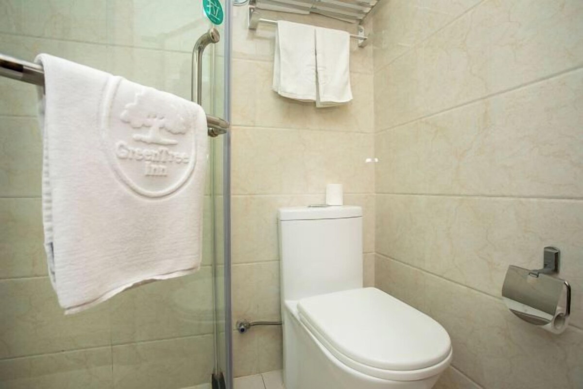 Un baño con inodoro, cabina de ducha de vidrio y toallero con toalla.