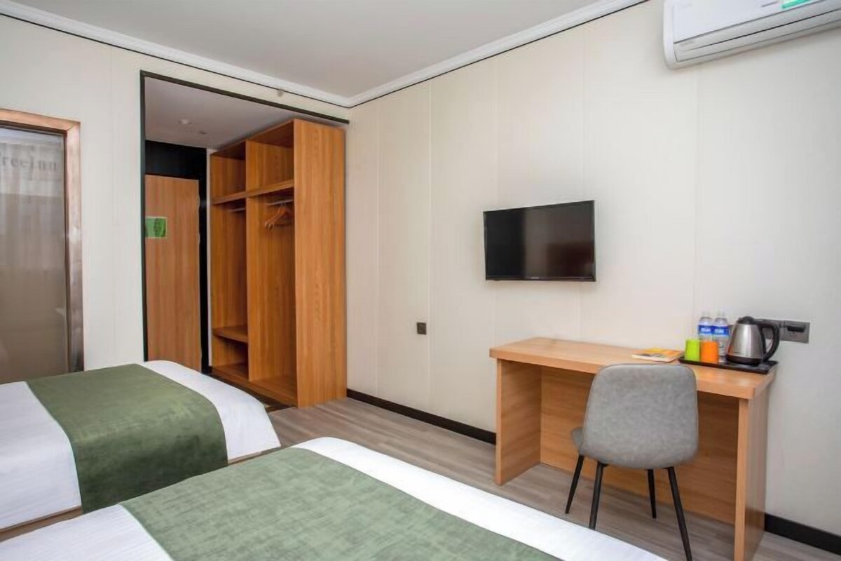 Una habitación de hotel con dos camas, un escritorio, una silla, un televisor y un armario.