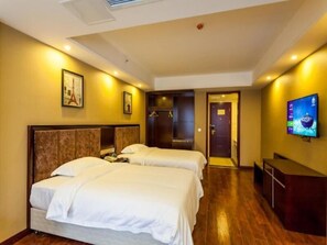 Ein Hotelzimmer mit zwei Betten, einem Fernseher und einer Tür zu einem Badezimmer.