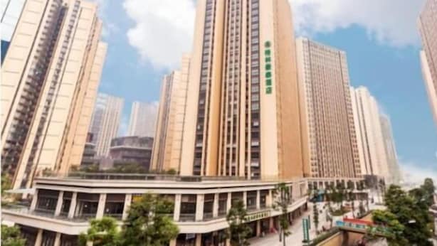 Korkea kerrostalo, jossa on useita kerroksia, keskeinen sisäpiha ja ympäröivää viheraluetta.