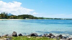 A coastal landscape with clear blue water, a sandy beach, and a forested island in the distance. - La Case Bois Creoles (the sea) (Albion)