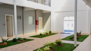 Un espacio interior amplio con un jardín central, paredes blancas y un techo alto.