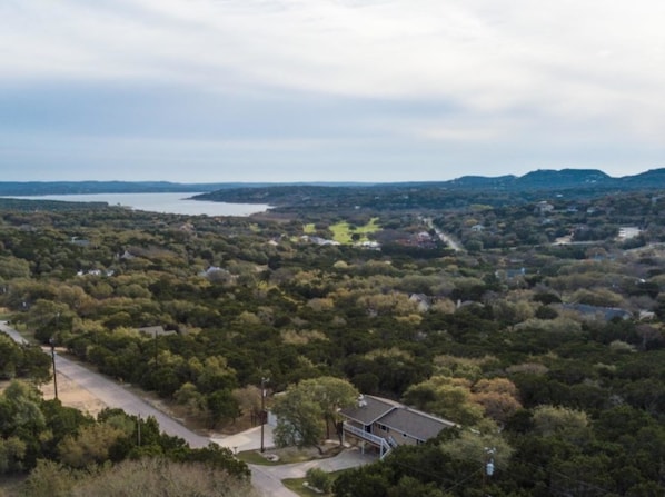 A residential area with a house near a road, surrounded by dense trees and a body of water in the distance. - Scriv's Haus (Winters)