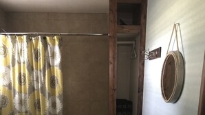 A bathroom with a shower curtain, a bathtub, a wooden vanity, a toilet, and a rug.