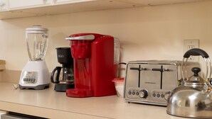 Eine Küche mit weißen Schränken, einem Mixer, einer roten Kaffeemaschine, einem Toaster und einem Wasserkocher.